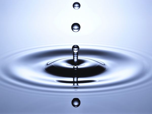A small water drop fall on water surface and jump back before the second one to collide with it.